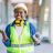 avatar-4 Portrait of woman engineer at building site looking at camera with copy space. Mature construction manager standing in yellow safety vest and white hardhat with crossed arms. Successful confident architect at construction site